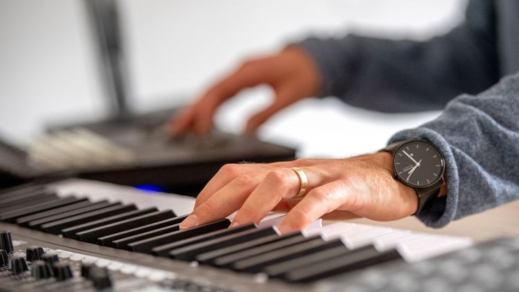 A hand on the keyboard of a piano.
