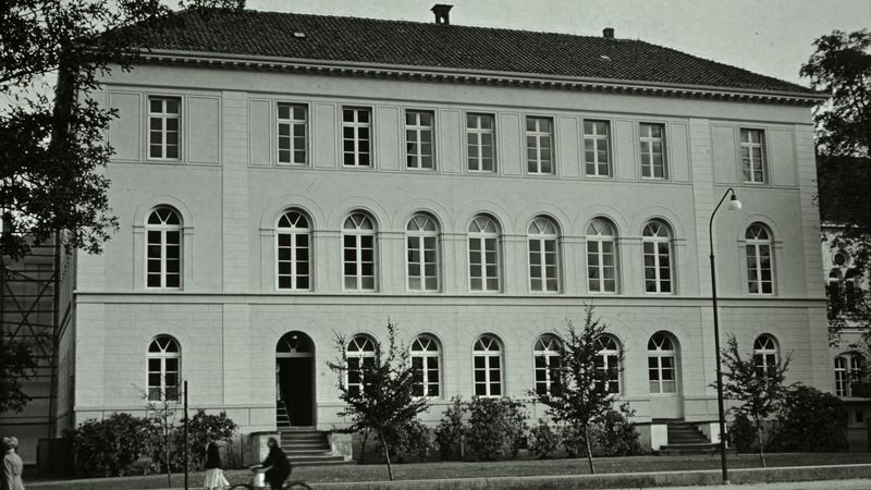 Das Bild zeigt das alte Lehrerseminar von der Peterstraße aus. Zu erkennen ist ein zweistöckiges Gebäude mit Fenstern. Die Architektur ist funktional gehalten.
