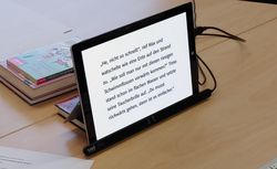 Ein Tablet zeigt Text aus einem Kinderbuch, am unteren Rand ist ein Gaze Tracker befestigt.
