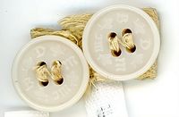 Object TO421, two round buttons, each with four holes and beaded edge. The letters B D M J M are stamped on the surface