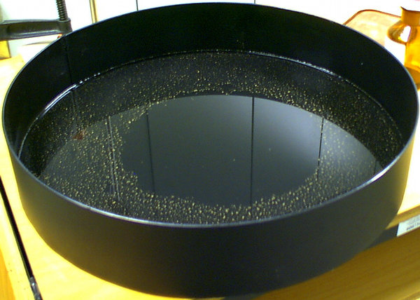 Foto eines Wasserbeckens mit einem runden Olfilm darauf.