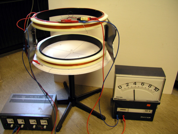 Foto vom Messaufbau mit einer Helmholtzspule, einer Spannungsquelle und einem Magnetfeldmessgerät.
