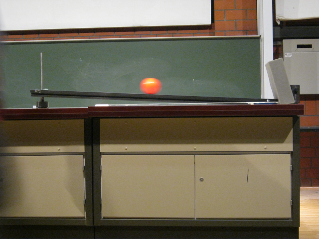 Foto eines roten Balles auf einer schiefen Ebene.