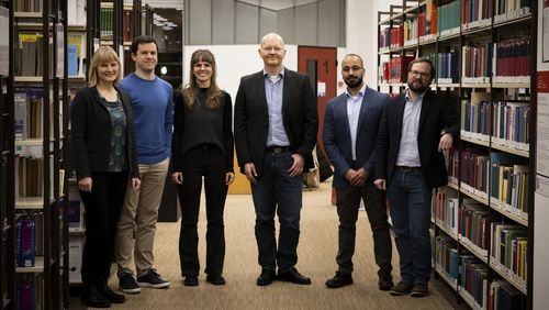 The picture shows the award-winning lecturers between bookshelves in the library.