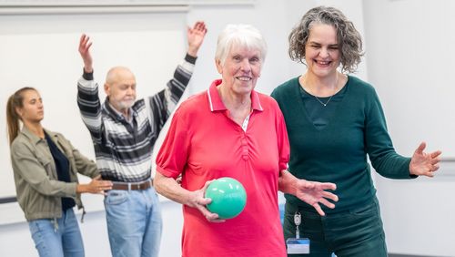 Tania Zieschang assists a participant holding a ball in her hand during an exercise.