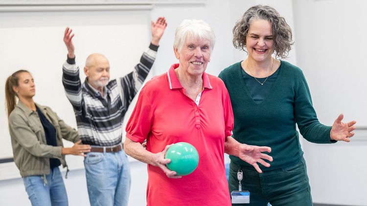 Tania Zieschang assists a participant holding a ball in her hand during an exercise.