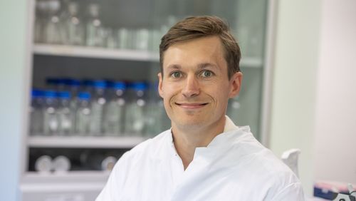 Portrait of Volker Kinast in a lab coat in the office.