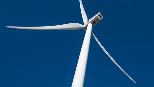 Die Rotoren einer Windkraftanlage, von unten gegen den stahlblauen Himmel gesehen. 