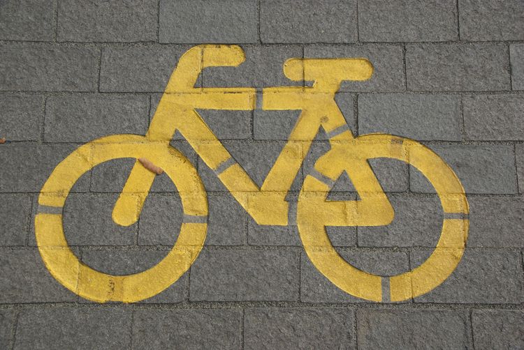 The pictogram of a bicycle is painted in yellow on a paving stone.