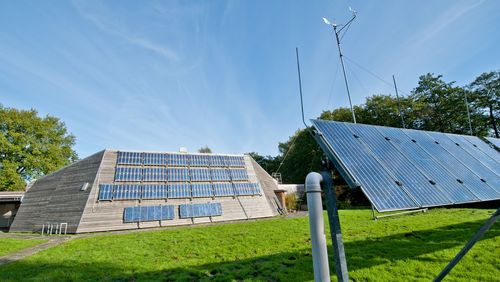 The Energy Lab with its historical solar panels can be seen in front of trees and the blue sky.