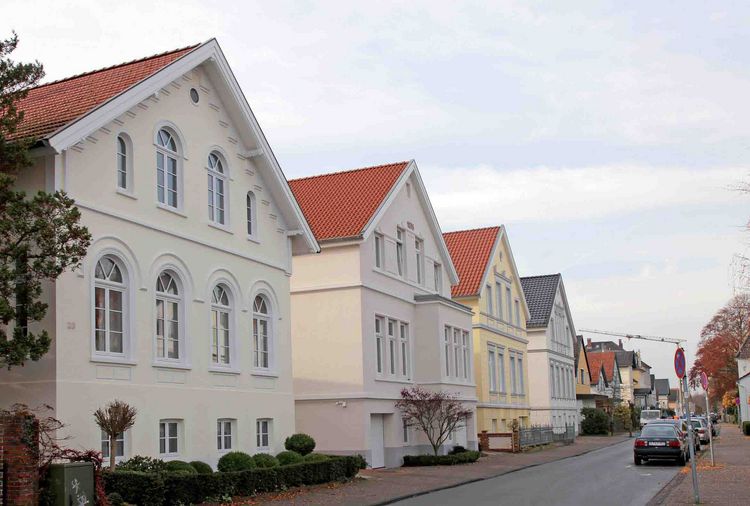  A row of "Hundehütte"-style houses in Oldenburg with red tile roofs and well-maintained gardens.