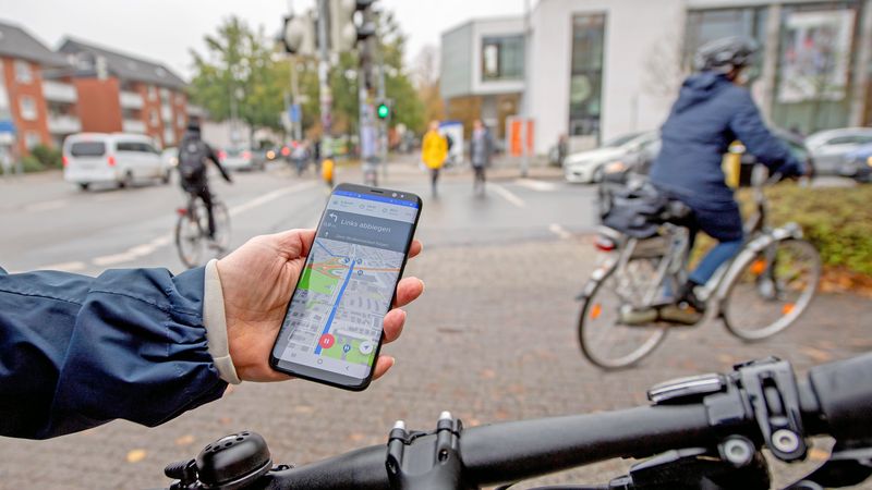 Eine Hand hält ein Smartphone mit Navigationsapp für Radfahrer an der Kreuzung Uhlhornsweg/Ammerländer Heerstraße in Oldenburg.
