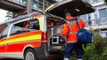 Mann mit orangener Jacke des Deutschen Roten Kreuzes belädt das Gemeindesanitäterfahrzeug: Ein Van mit großer Ladefläche, orange-gelber Beklebung und dem Schriftzug "Gemeindenotfallsanitäter".