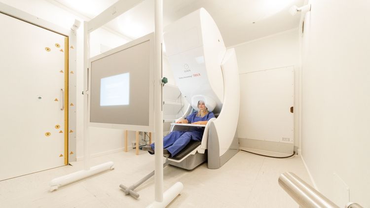Test person sits in the measuring device in the middle of a completely white room. 
