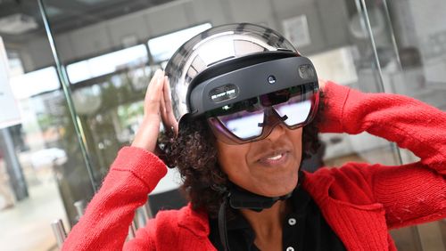 Eine junge Frau präsentiert den Prototypen des smarten Helms: Sie trägt eine Virtual-Reality-Brille und einen silbernen Fahrradhelm.