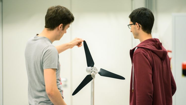 Zwei Studenten vor einem Windrad mit einem Durchmesser von etwa einem Meter.