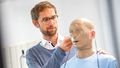 Kai Siedenburg in the hearing lab with a mannequin wearing hearing aids.