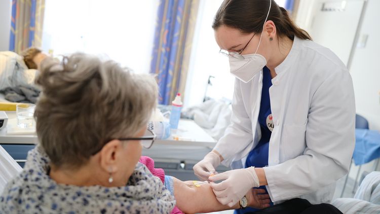 Antonia nimmt bei einer Patientin Blut ab.