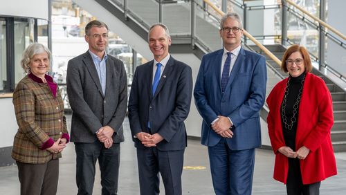 Die fünf Personen stehen nebeneinander vor der Treppe im Hörsaalzentrum.