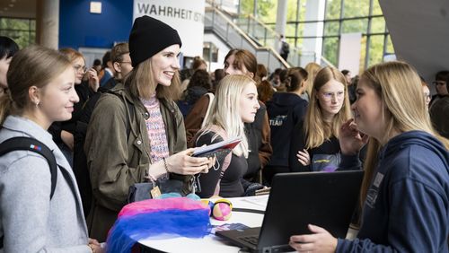The info market in the foyer of the lecture hall centre. Students checking out the services on offer at a stand. 