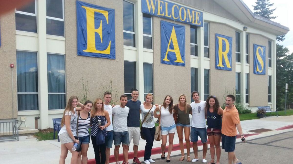 Gruppe Studierender steht vor einer Hauswand der University of Northern Colorado, an der auf Plane geschrieben steht "Welcome Bears"