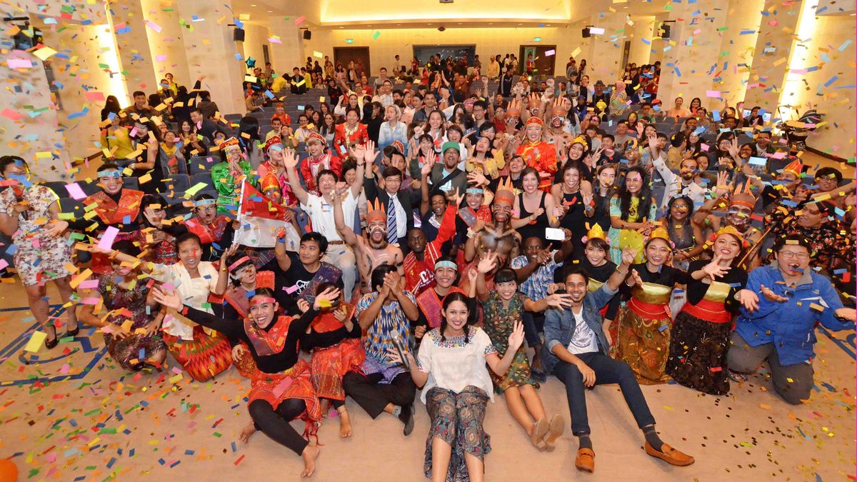 A large group celebrates in a hall at NDHU with confetti and an exuberant atmosphere.