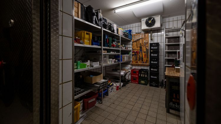 Mit Showutensilien befüllte Regale in einem weiß gefließten Raum. 