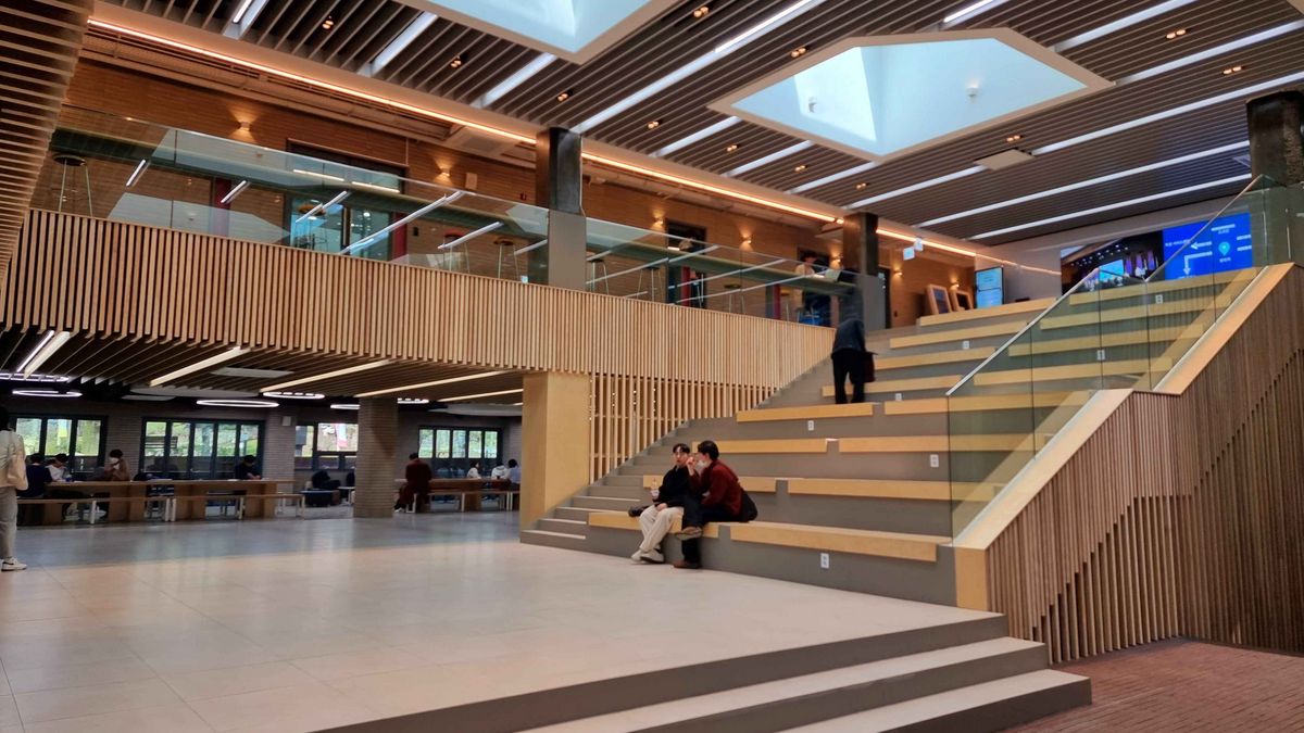 The entrance area of the University of Seoul with high ceilings and luminous elements. A wide staircase leads to an upper level.