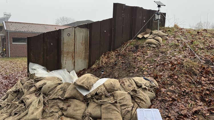 A measuring station on an artificial dyke with sandbags stacked in front of it.
