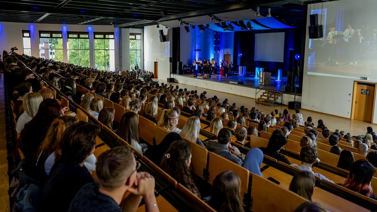 A packed Audimax: the students are following the programme on stage.