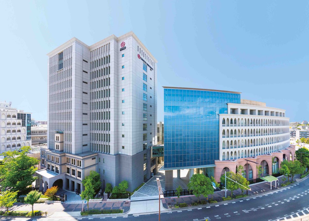 in hohes Gebäude auf dem Nagoya Campus mit Glas- und Steinfassade.