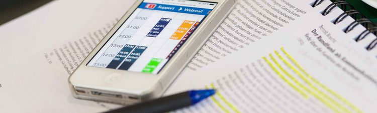 Ein Smartphone mit einer App-Oberfläche liegt auf einem Textdokument über Berthold Brecht.