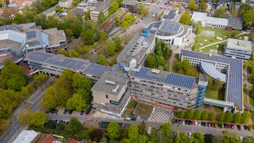 An aerial view from above, showing a large building with photovoltaic systems on the roof.