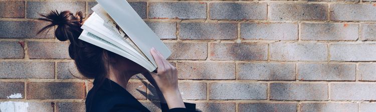 A woman covers her face with a white book