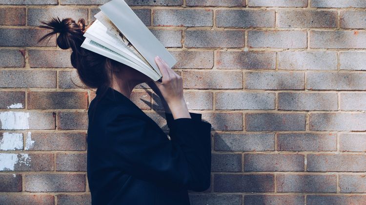 A woman covers her face with a white book