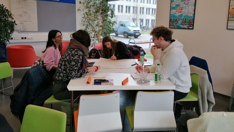 The picture shows a group of students at a workshop in the university's Intercultural Meeting Centre. They are working on a poster.