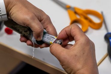 Zwei Hände öffnen das Röhrchen, zum Vorschein kommt ein Mikrochip.