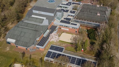 Luftaufnahme von schräg oben zeigt die Dächer des Sportzentrums mit den Modulen. 