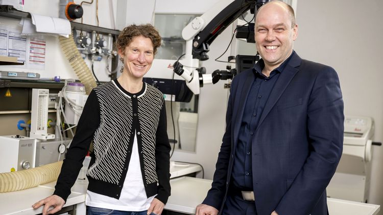 Das Bild zeigt Miriam Liedvogel und Henrik Mouritsen. Sie stehen in einem Labor vor technischen Apparaturen und lächeln in die Kamera.