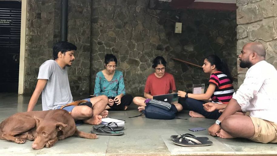 Eine Gruppe von Menschen sitzt auf dem Boden und lernt, ein Hund liegt in der Nähe.
