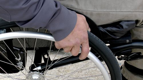 Close-up of a hand on the wheel of a wheelchair.