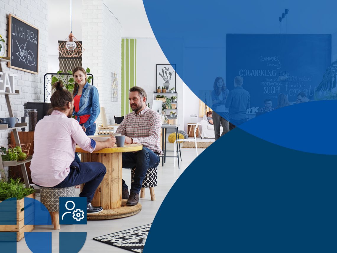 Many people sit and stand in a co-working office and talk to each other.