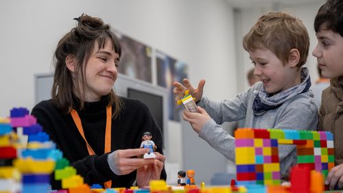Einblick in die Philosophiewerkstatt der Uni Oldenburg: Eine Studentin im Gespräch mit zwei Kindern. Im Vordergrund sind Duplo-Legobausteine.