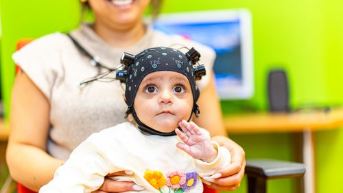 A few-months-old child wears a cap with several light-emitting diodes.