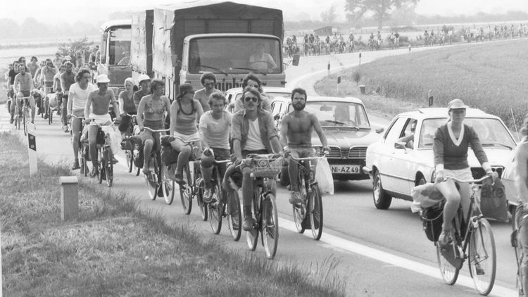 There are lots of people on bikes riding along a country road.
