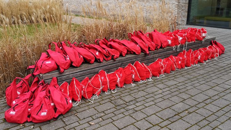 42 rote Rucksäcke liegen auf und vor einer Bank vor dem Experimentierhörsaal in Wechloy.