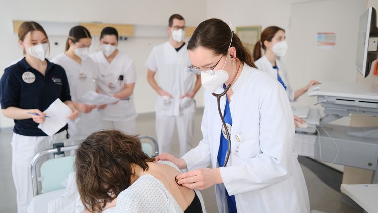 Antonia hört mit dem Stehoskop eine Patientin ab.