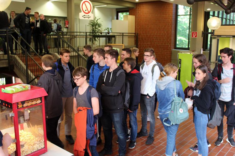 Schülerinnen und Schüler warten vor der Popcorn-Maschine am Infostand der Fachschaft