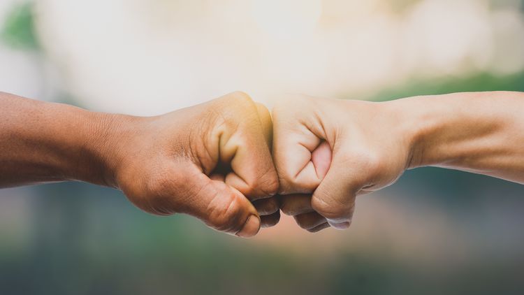 The fists of two people touch.