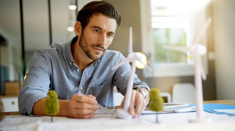 A young man works in an office on models of wind turbines.